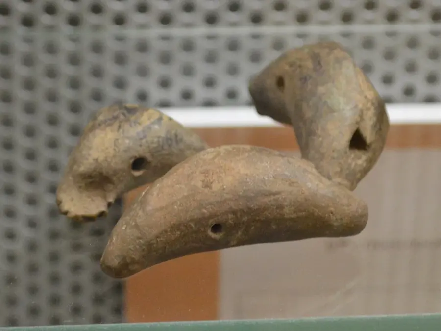 Two small clay whistles shaped like birds, with their finger holes showing
