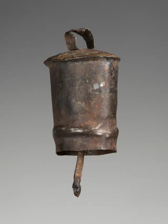 A dark forged iron sheep bell with a loop at the top for its strap