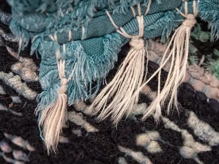 Knotted cotton fringe hanging from the end of a woven runner