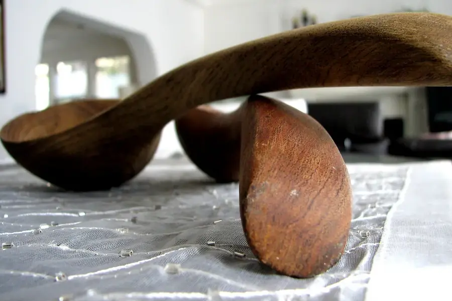 Two carved wooden spoons with deep bowls resting on a table